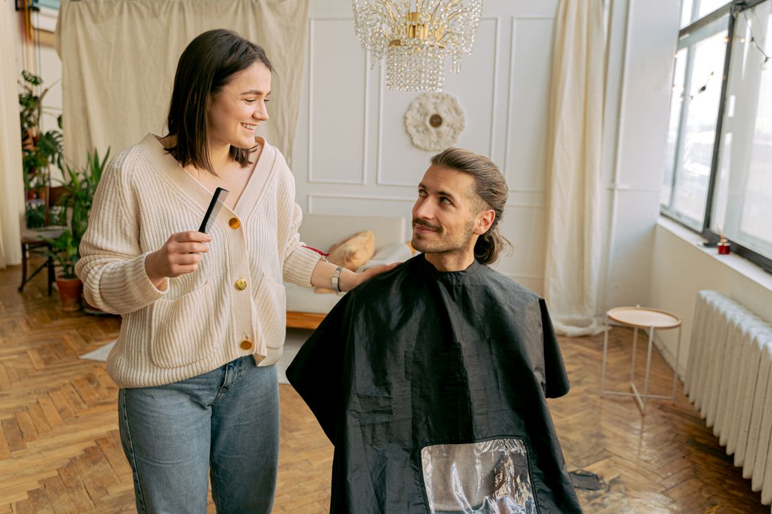 Coiffeuse souriante et son client satisfait dans un salon lumineux et chaleureux