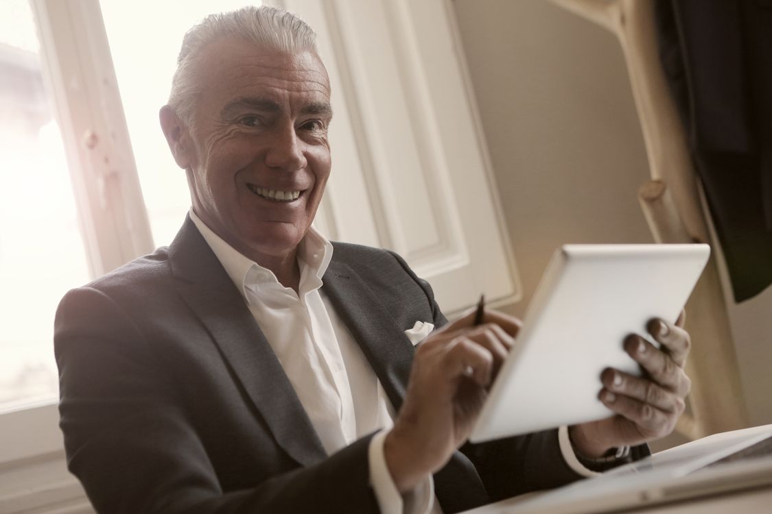 Gérant souriant consultant les résultats de son activité sur une tablette